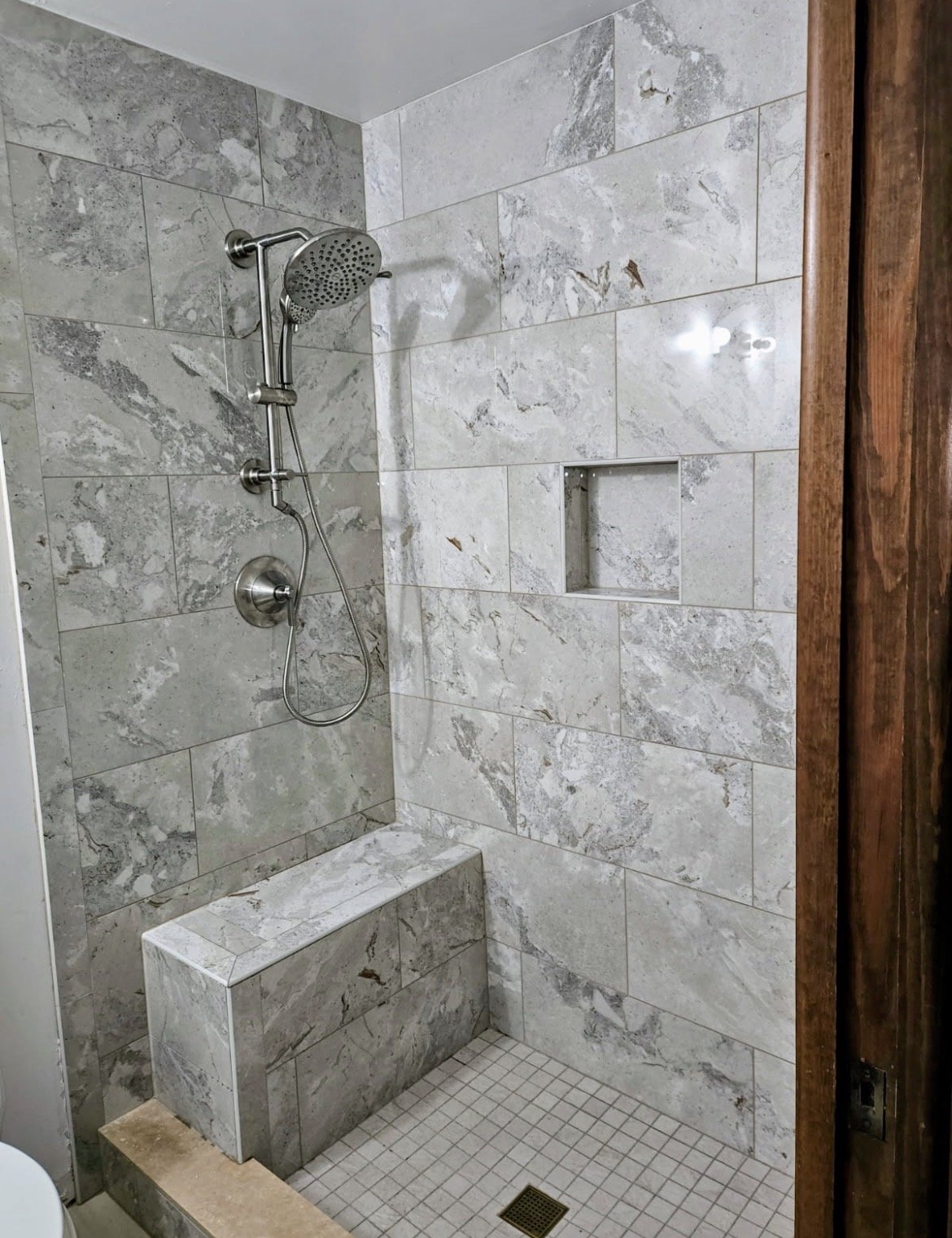 Custom tiled walk-in shower with a bench and niche