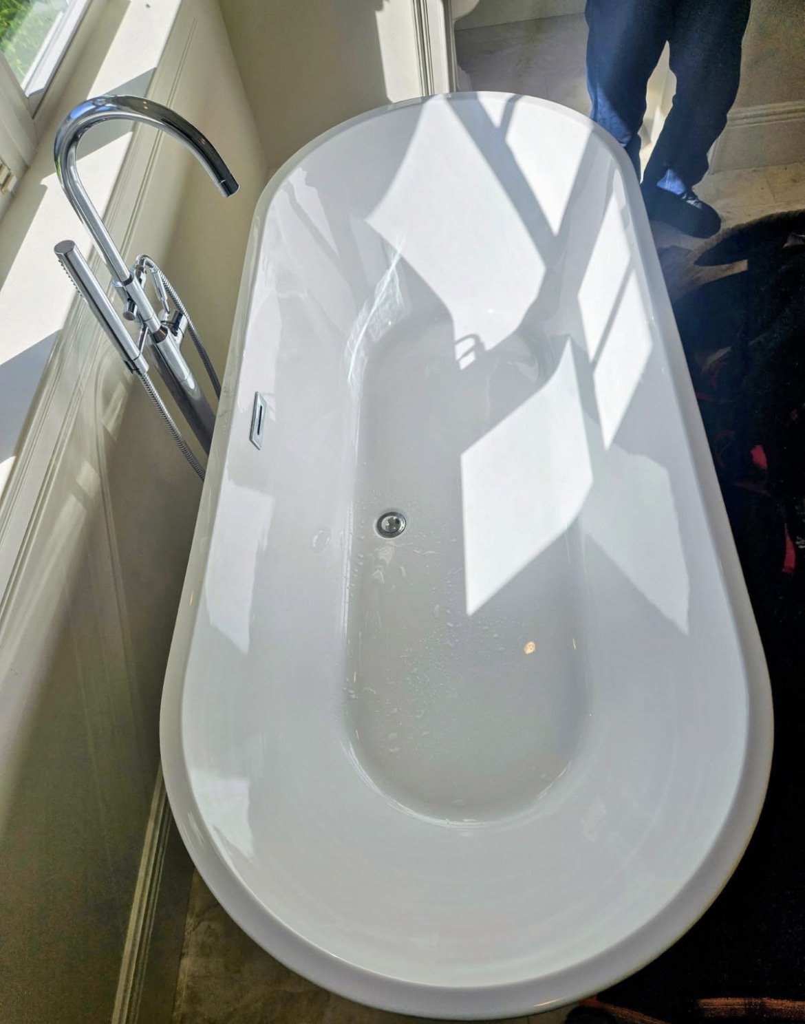 Freestanding soaking tub with a chrome floor-mounted faucet